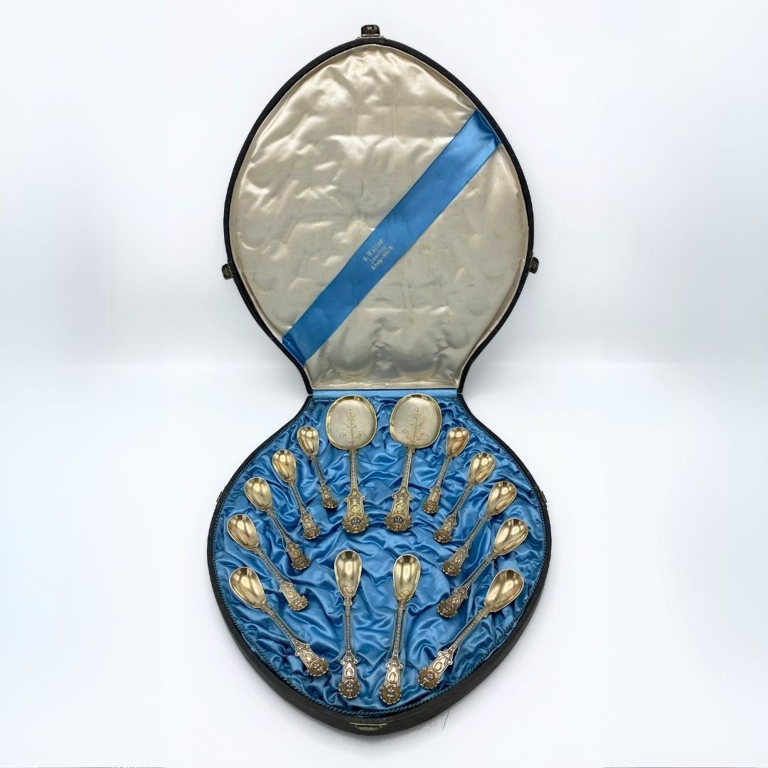Een cassette met blauwe bekleding met zilveren lepels en opscheplepels